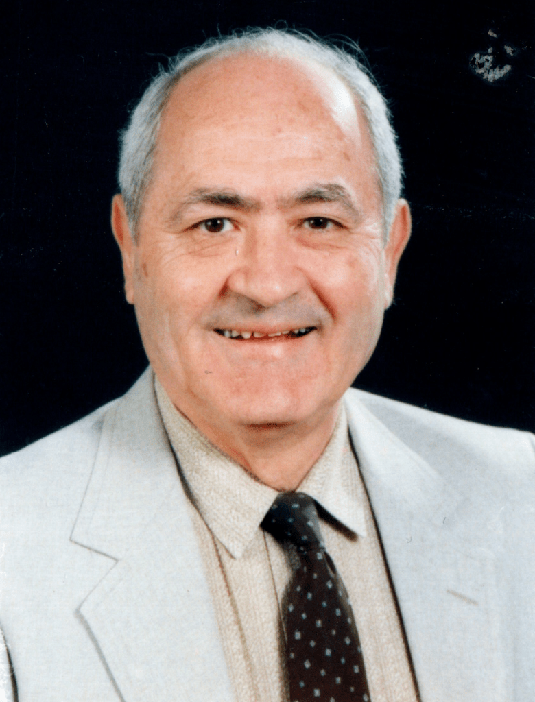 A headshot of Dr. Naim Atiyeh smiling. He's wearing a gray blazer and a black tie.