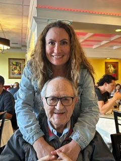 Lyna, smiling with her arms wrapped around her father's shoulder's. Naim smiles at the camera while wearing glasses.